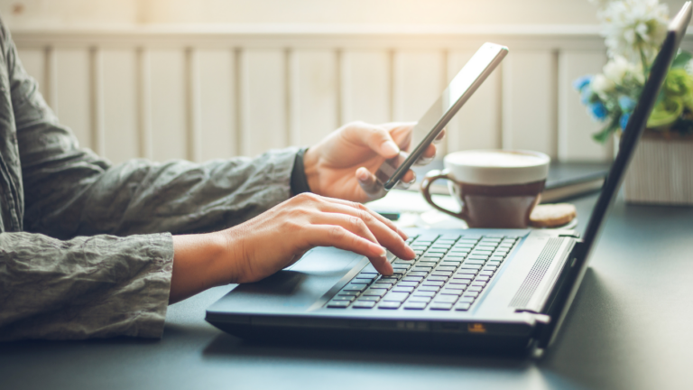 Someone uses their laptop at the same time as their phone in an office environment. NurtureCloud is fitting into this new way of life in real estate.